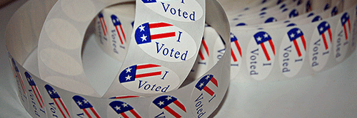 roll of colorful "Voted" Stickers on a table