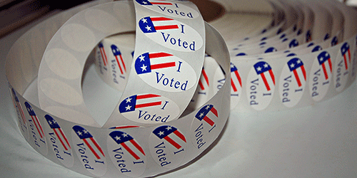 roll of colorful "Voted" Stickers on a table
